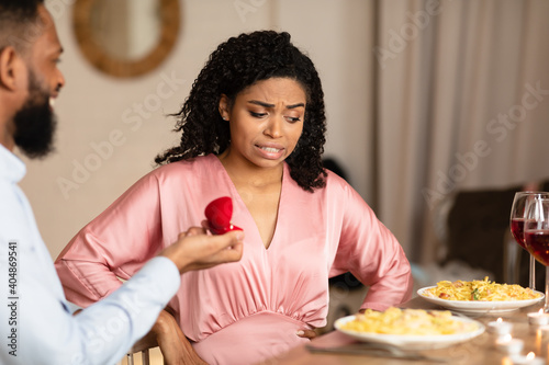 Black man making proposal with ring  unsure woman thinking