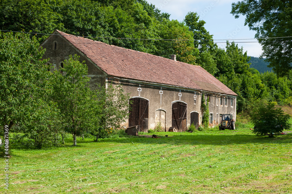 farm shed with tractor surrounded by deciduous trees