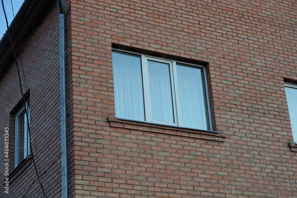 one white square window on a brown brick wall of a building one white square window on a brown brick wall of a building