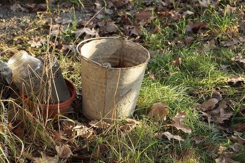 one gray dirty metal bucket stands in the green grass outside