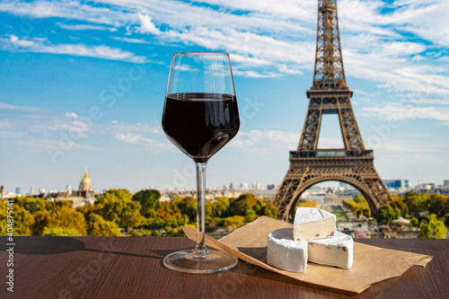 Glass of wine with brie cheese on Eiffel tower and Paris skyline background. Sunny view of glass of red wine overlooking the Eiffel Tower in Paris  France