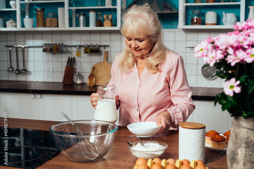 Cincematic image of a senior woman baking and preparing food in her beautiful kitchen photo