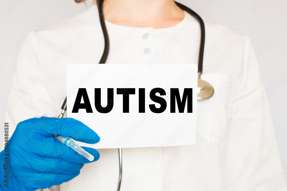 The doctor's blue - gloved hands show the word AUTISM - . a gloved hand on a white background. Medical concept. the medicine The doctor's blue - gloved hands show the word AUTISM - . a gloved hand on a white background. Medical concept. the medicine