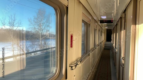 In the corridor of a compartment car of a train in motion, a flashing winter landscape outside the window, a bright sunny day on a journey
