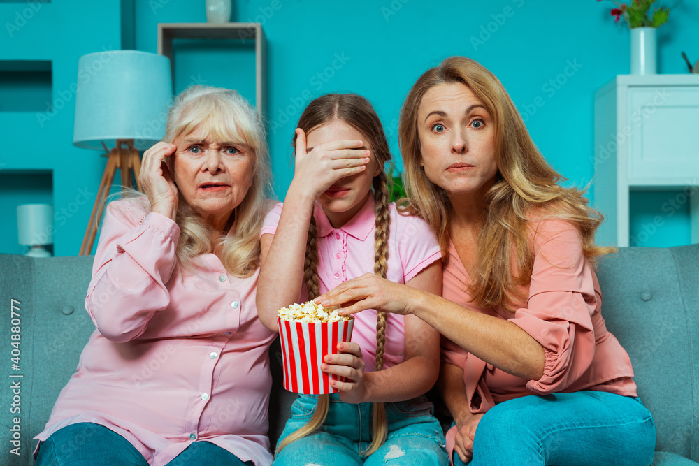 Fototapeta premium Cinematic portrait image of grandmother, mother and grandaughter sitting on the couch