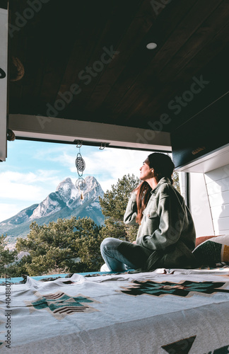 image of a young brunette woman, stretched out inside a camper van, looking towards Pedraforca mountain