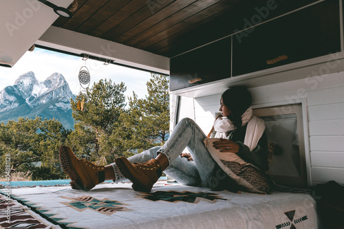 image of a young brunette woman, stretched out inside a camper van, looking towards Pedraforca mountain
