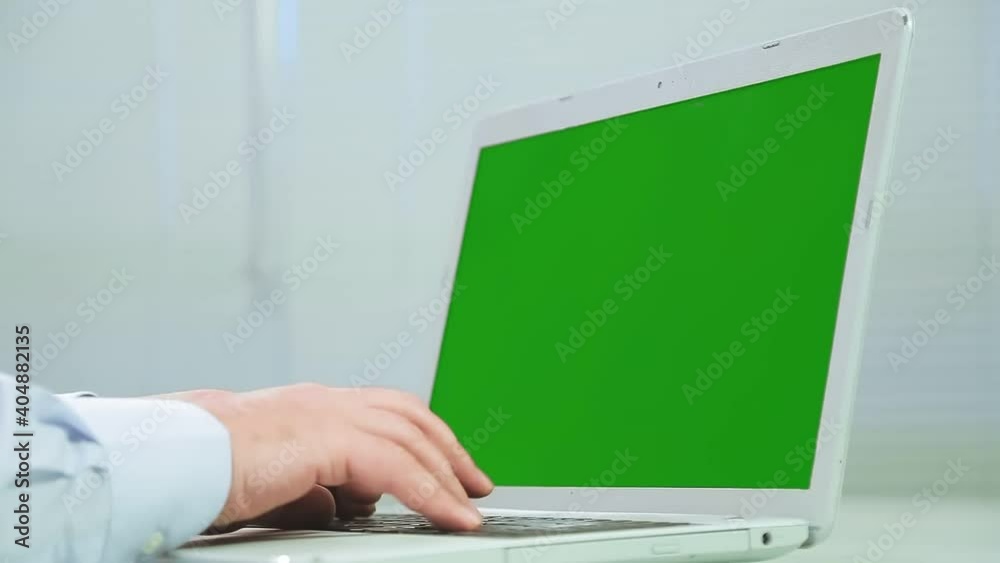 Male hands are typing on a green screen laptop keyboard. Medium plan Male hands are typing on a green screen laptop keyboard. Medium plan