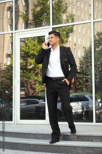 Handsome man talking on smartphone on city street