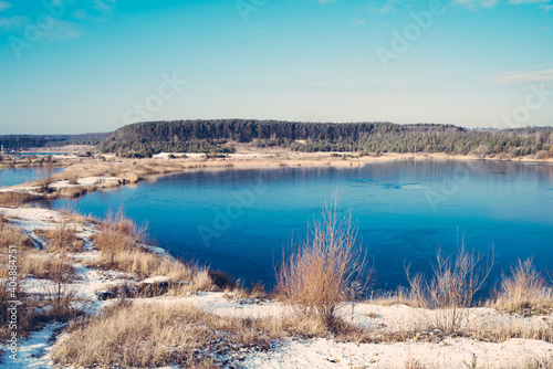 Lake in the middle of the forest with blue water on a sunny early spring day