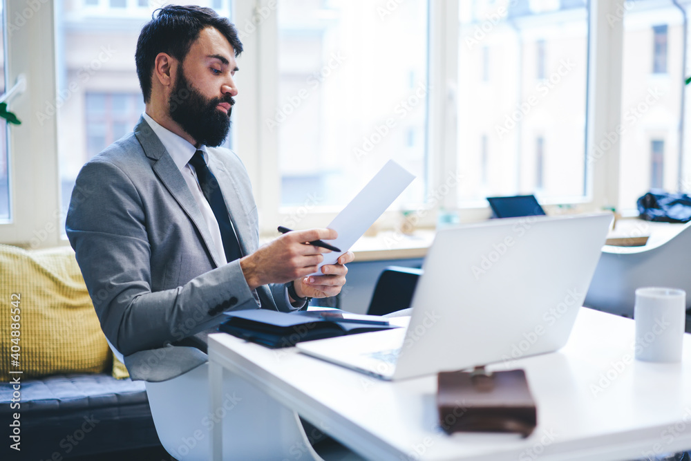 Focused businessman looking through documents in office Focused businessman looking through documents in office