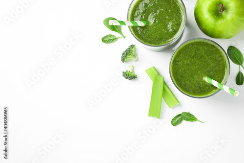 Delicious green juice and fresh ingredients on white background, flat lay. Space for text