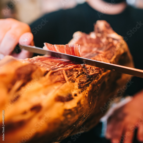 A man's hands in a restaurant Spanish Iberian ham cutter. Close-up meat.