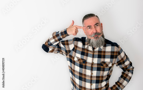 retro styled bearded man in plaid shirt putting the index finger of his right hand to his temple in clear sign of thought or idea