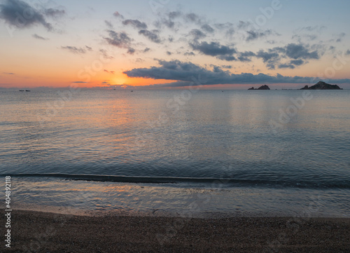 Sunrise with the red orange sun raising up from the sea with dark clouds at beach Spiaggia di Santa Maria Navarrese, Sardinia, Italy