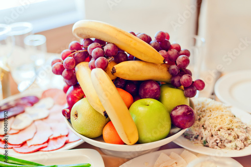 Grape  apples  pears  bananas and other fruits in a vase on a festive table