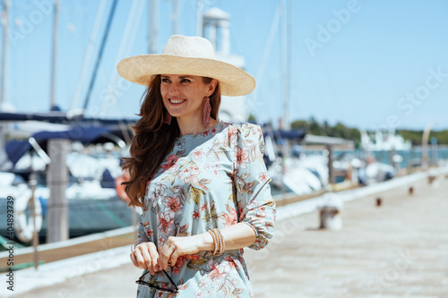 happy stylish solo tourist woman in floral dress on pier photo