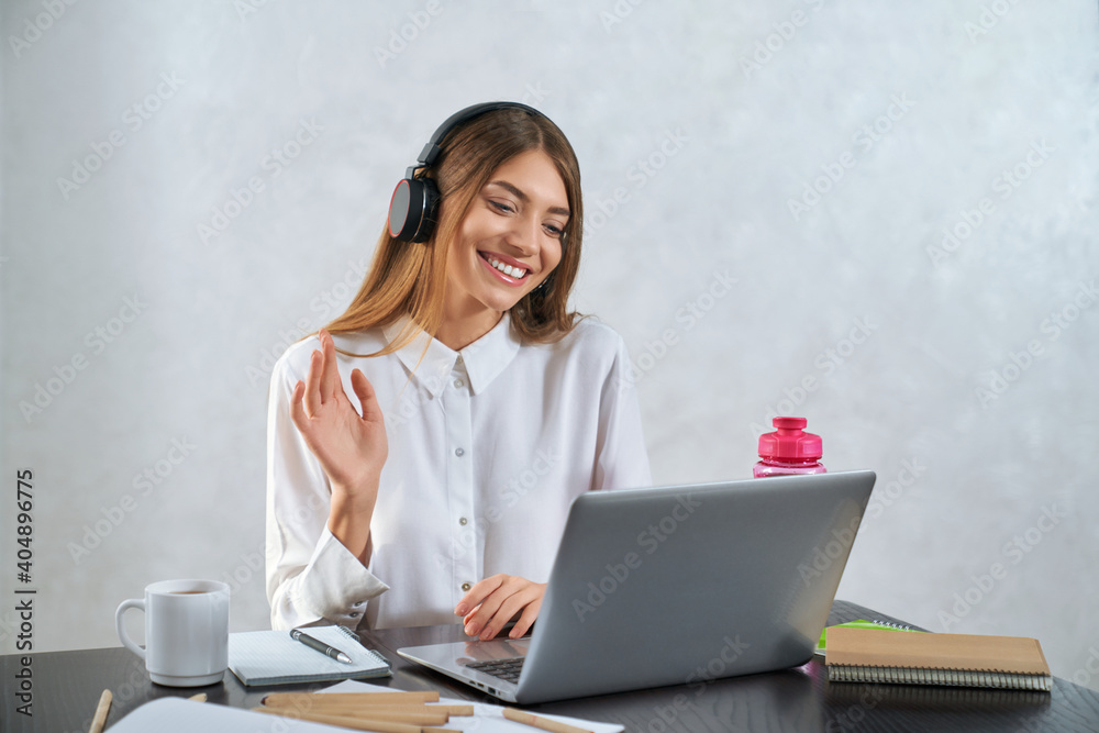 Woman waving and talking during online education on laptop Woman waving and talking during online education on laptop