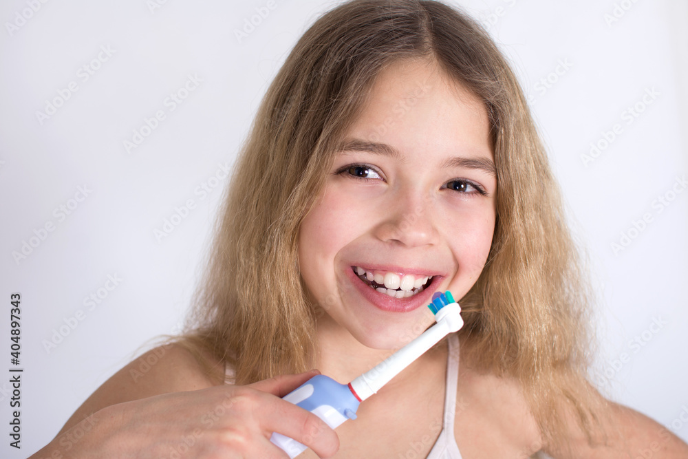 Young girl portrait with rotating-oscillating electric toothbrush isolated on white background. Oral hygiene and white teeth concept. Young girl portrait with rotating-oscillating electric toothbrush isolated on white background. Oral hygiene and white teeth concept.