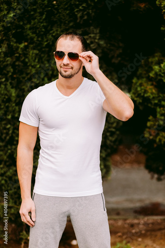 man wearing blank white t-shirt outdoors. Male in blank white t-shirt v collar, front view outdoors. Design men t shirt template and mock-up for print 