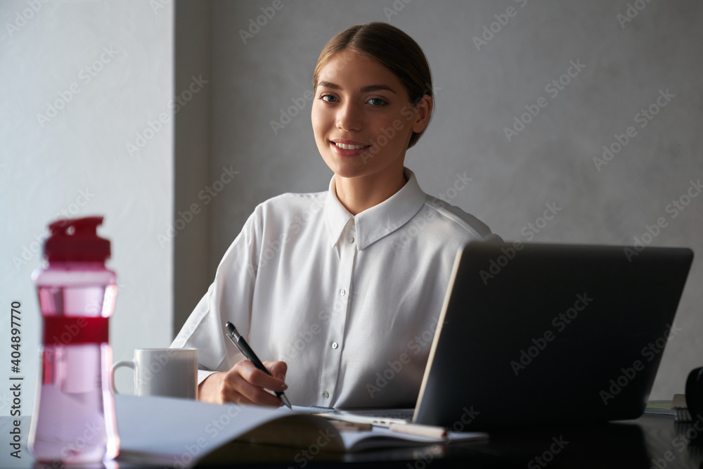 Woman using laptop and smiling while working at home Woman using laptop and smiling while working at home