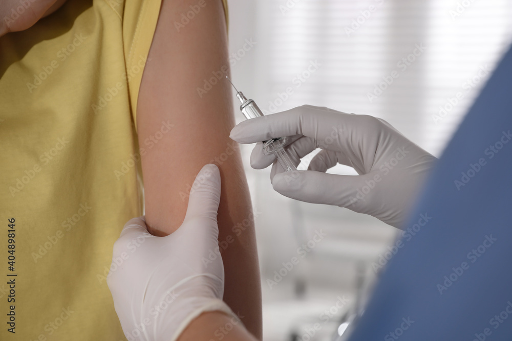 Doctor vaccinating young woman against Covid-19 in clinic, closeup Doctor vaccinating young woman against Covid-19 in clinic, closeup