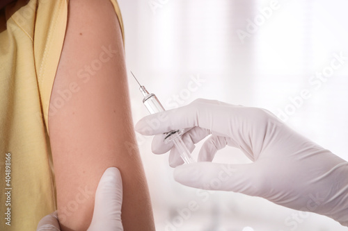 Doctor vaccinating young woman against Covid-19 in clinic  closeup