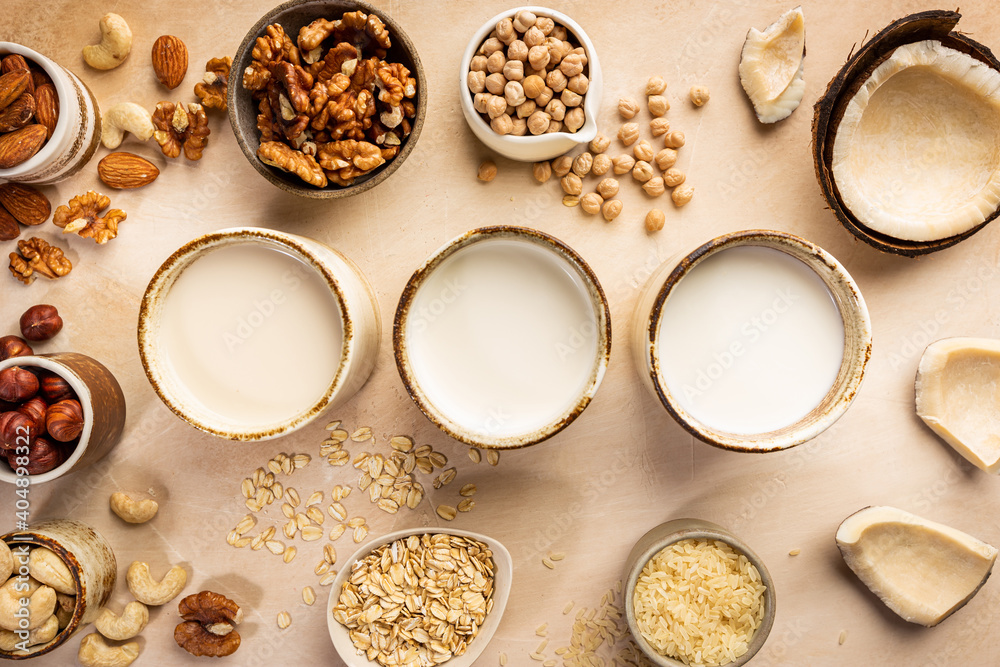 Vegan non dairy plant based milk in cupes and ingredients on light background. Lactose free milk substitute. Top view. Vegan non dairy plant based milk in cupes and ingredients on light background. Lactose free milk substitute. Top view.