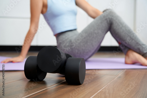 Close up of woman sitting on floor with two black dumbbells