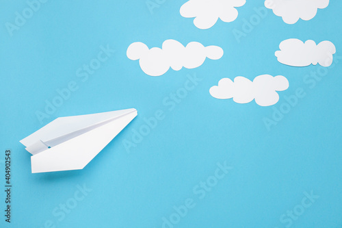 Origami plane and paper clouds . End of pandemic concept. Opening of borders and resumption of flights. Top view. Flat lay