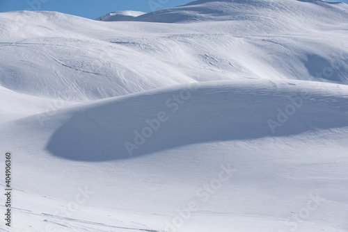 un bel paesaggio di montagna innevato, delle dune di neve in luce-ombra sembrano quasi un deserto.