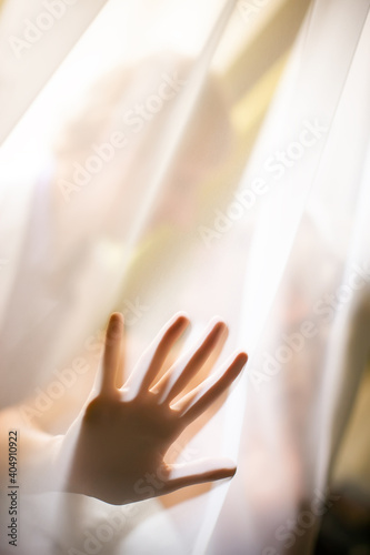 Silhouette of the palm of a man's hand with spread fingers under an organza against the background of a kissing couple in love. Focus concept.