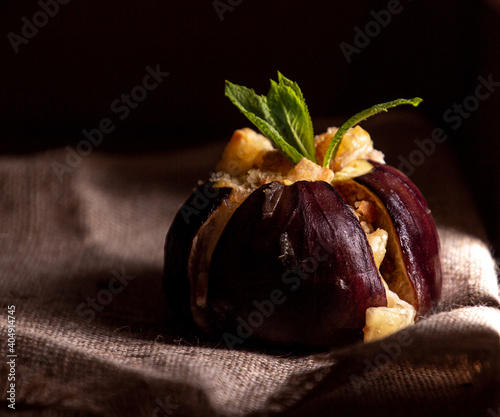 Ripe figs baked with cow's-milk cheese brie and camambert and sprinkled with bread crumbs, decorated with mint leaves aHealthy eating concept. Dark minimalism style photo