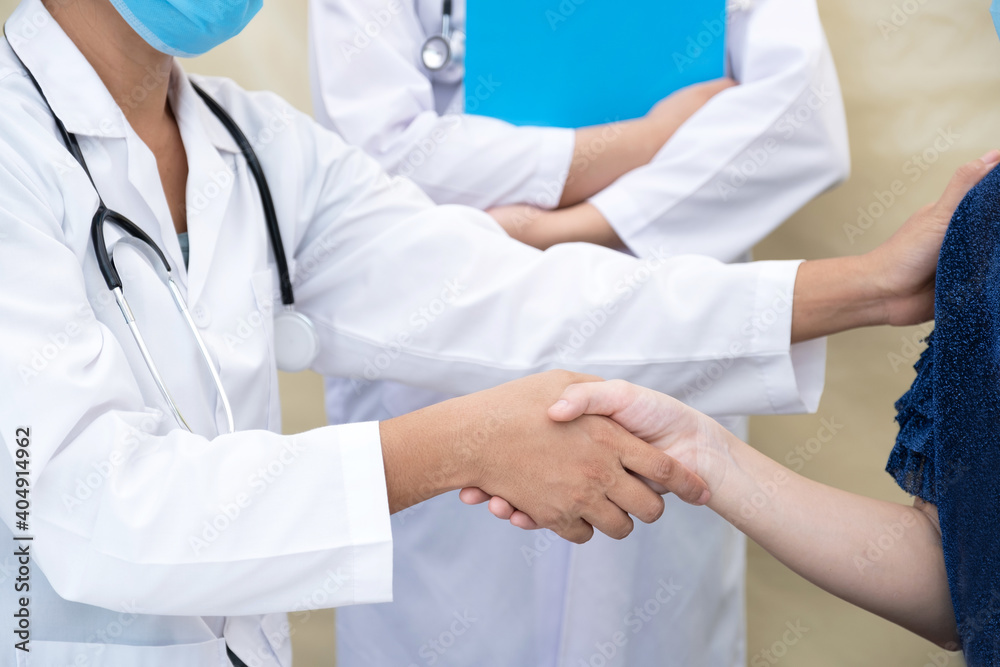 Hands shake, A doctor and a patient wearing a mask shake hands after completing treatment during the COVID outbreak, health medical checkup concept Hands shake, A doctor and a patient wearing a mask shake hands after completing treatment during the COVID outbreak, health medical checkup concept