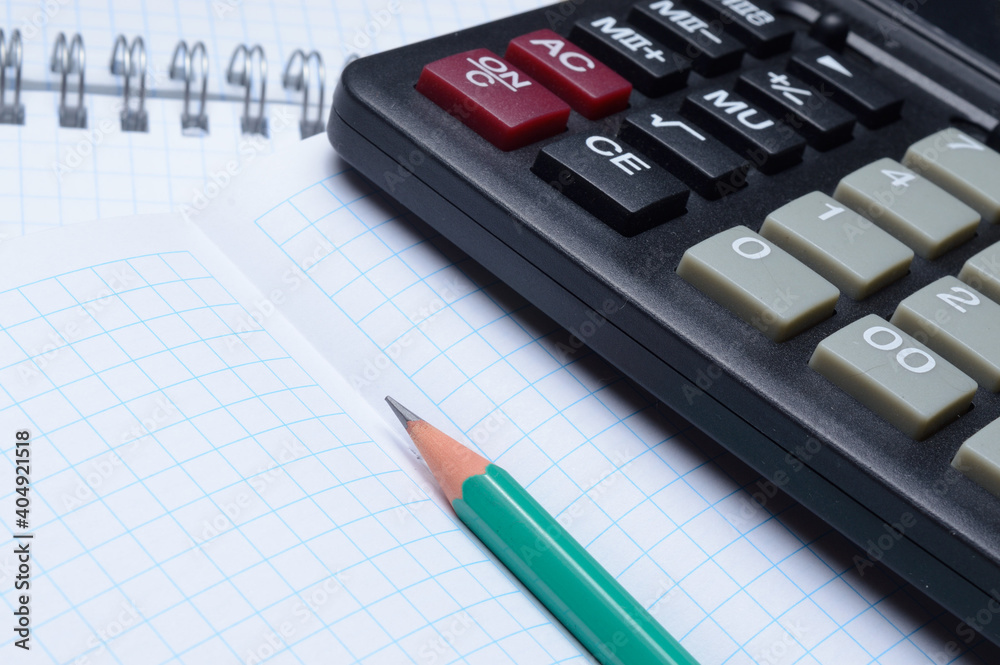 pencil and calculator are on an open notebook. close-up. pencil and calculator are on an open notebook. close-up.