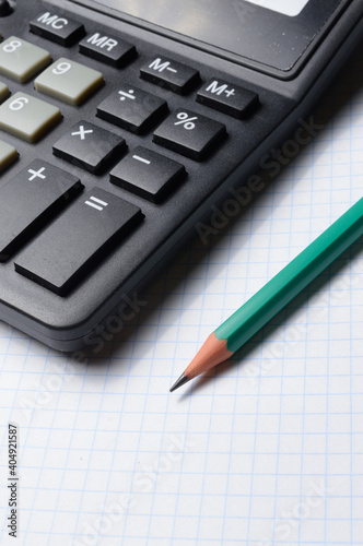 pencil and calculator are on an open notebook. close-up.