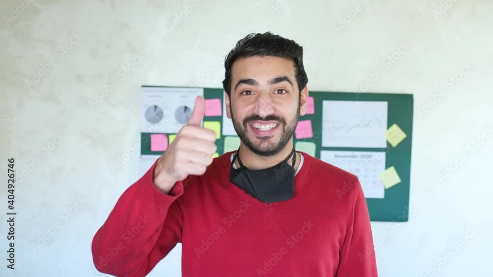 Arabic man gesturing in cheerful mood while wearing his mask from his home during quarantine time for his family ,work colleagues or during meeting Arabic man gesturing in cheerful mood while wearing his mask from his home during quarantine time for his family ,work colleagues or during meeting