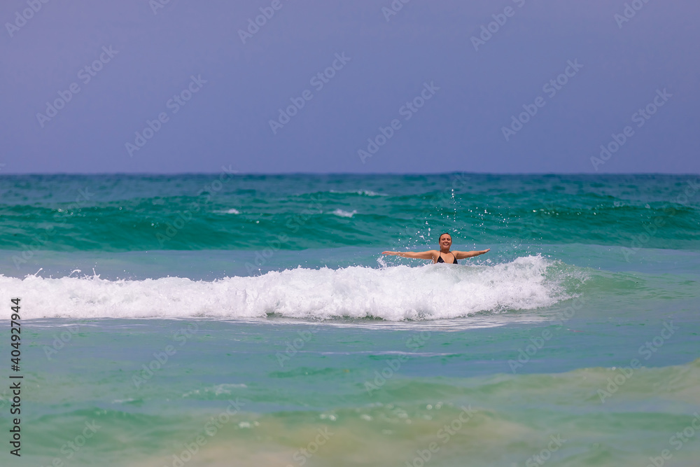 A young beautiful girl jumps into the sea with happiness, rejoices in the waves
