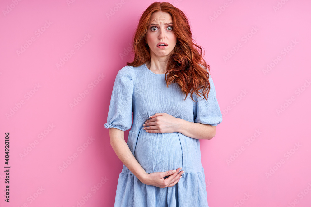 pregnant woman in dress having painful contraction, starting labor isolated on pink background, portrait, expecting baby - obrazy, fototapety, plakaty 