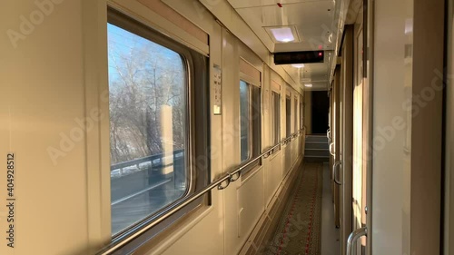 In the corridor of a compartment car of a train in motion, a flashing winter landscape outside the window, a bright sunny day on a journey