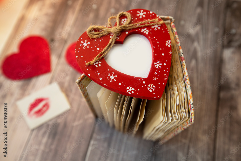 red photo frame in the shape of a heart lies on the pages of a vintage notebook