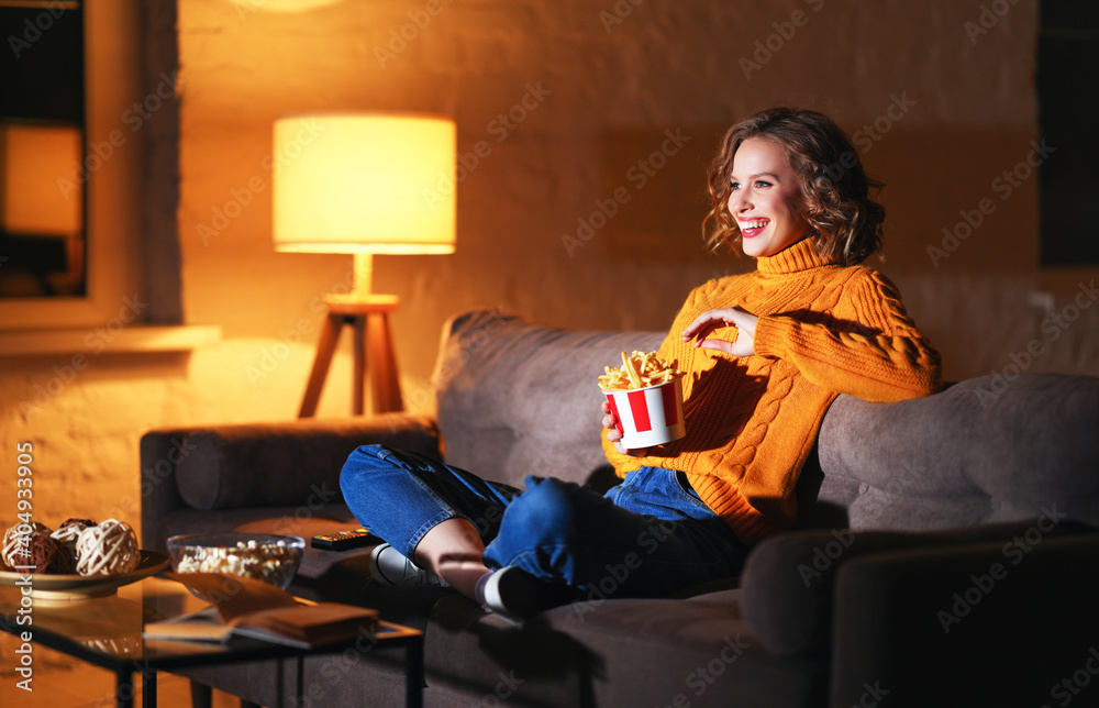 Excited female eating French fries and watching film - obrazy, fototapety, plakaty 