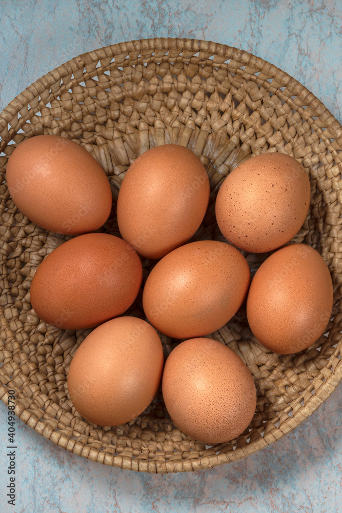 several fresh chicken eggs in a straw basket on a wooden background. Healthy eating concept. several fresh chicken eggs in a straw basket on a wooden background. Healthy eating concept.