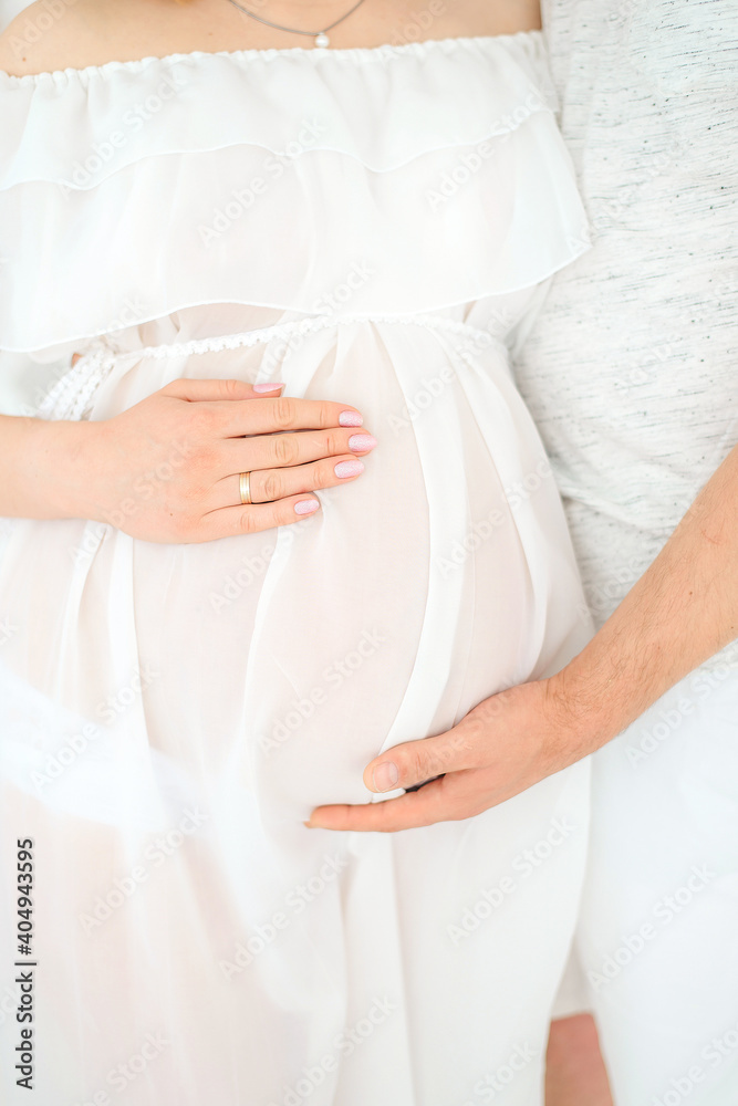Pregnant girl in a white penuary. Hands on your stomach. Pregnant girl in a white penuary. Hands on your stomach.