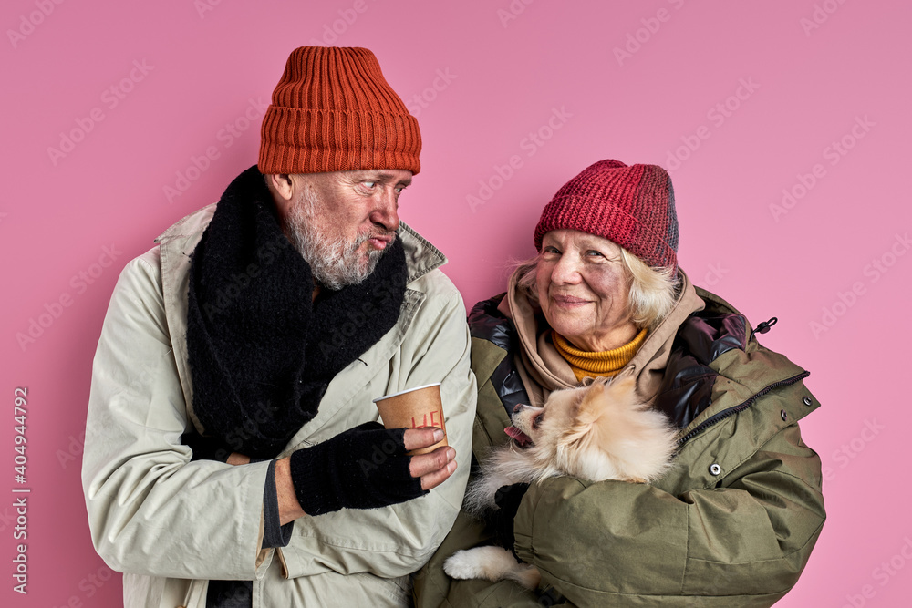 senior dirty man and woman have no home and money, but have adorable cute dog, posing at camera isolated on pink background
