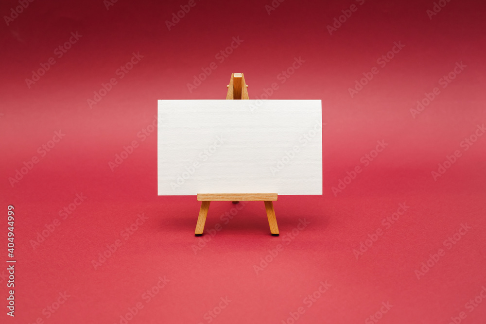 Wooden easel with white sheet. Red background. Wooden easel with white sheet. Red background.
