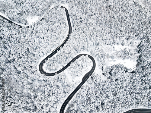 Aerial view of winding road in high mountain pass trough pine woods snowed © Rafaila Gheorghita