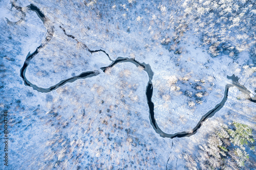 River in winter forest at sunset time, aerial view