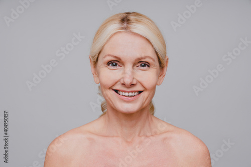 Smiling attractive mature woman with clean fresh skin close up isolated over grey background
