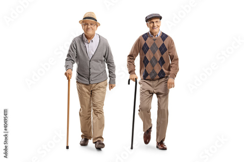 Full length portrait of two elderly men with canes walking towards camera